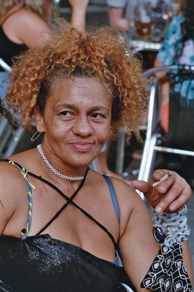 Portrait of a woman smiling looking off camera, whilst smoking in the street in Barcelona, Spain 