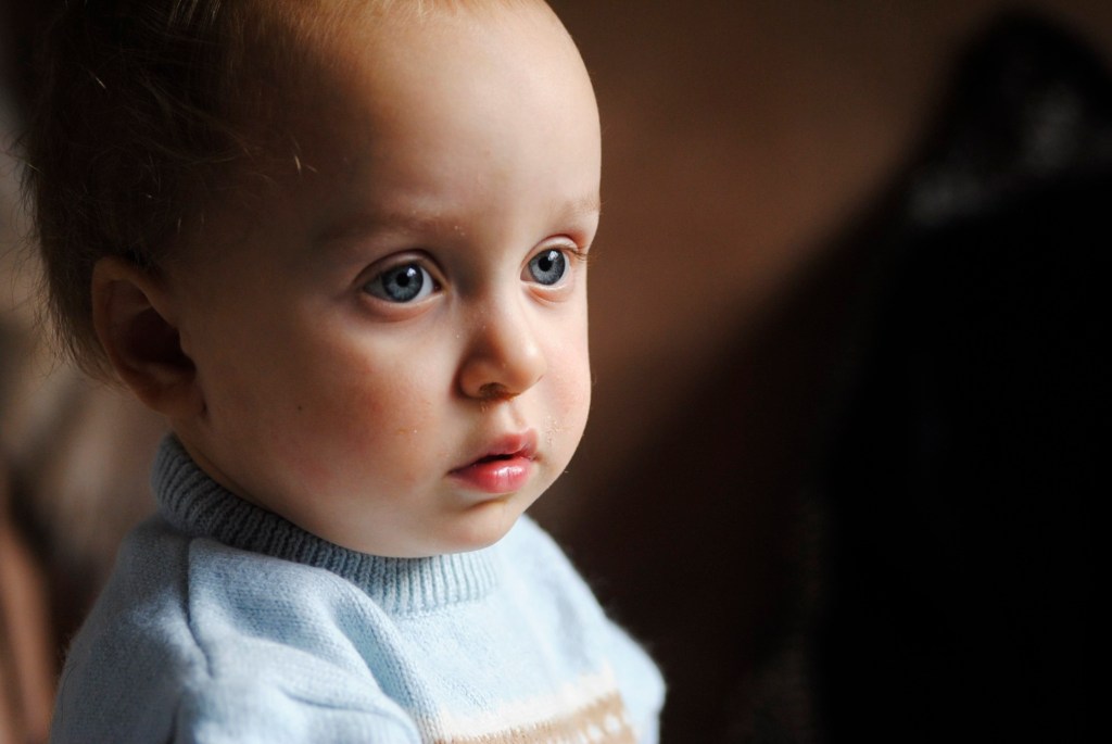 Portrait of a blue eyed baby looking off to the right of the image