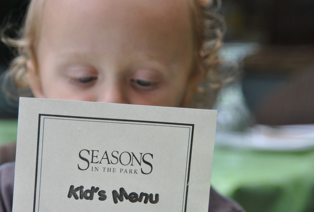 Portrait of toddler holding a children's menu, pretending to read 